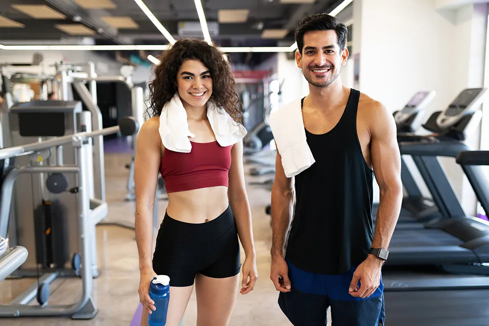 People smiling in gym, towels over shoulder